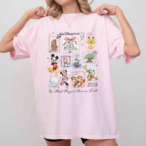 Puede incluir: Camiseta rosa claro con un dise&ntilde;o colorido de Disney. El dise&ntilde;o incluye a Mickey Mouse, Minnie Mouse, el Pato Donald y el Castillo de Cenicienta. Tambi&eacute;n se puede ver el texto "Walt Disney World" y "The Most Magical Place on Earth".