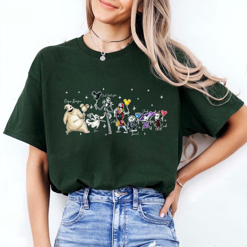 K&ouml;nnte beinhalten: Dunkelgr&uuml;nes T-Shirt mit einer farbenfrohen Grafik von Charakteren aus The Nightmare Before Christmas. Das Design umfasst Jack Skellington, Sally und andere Charaktere, mit Text &uuml;ber und unter den Charakteren.