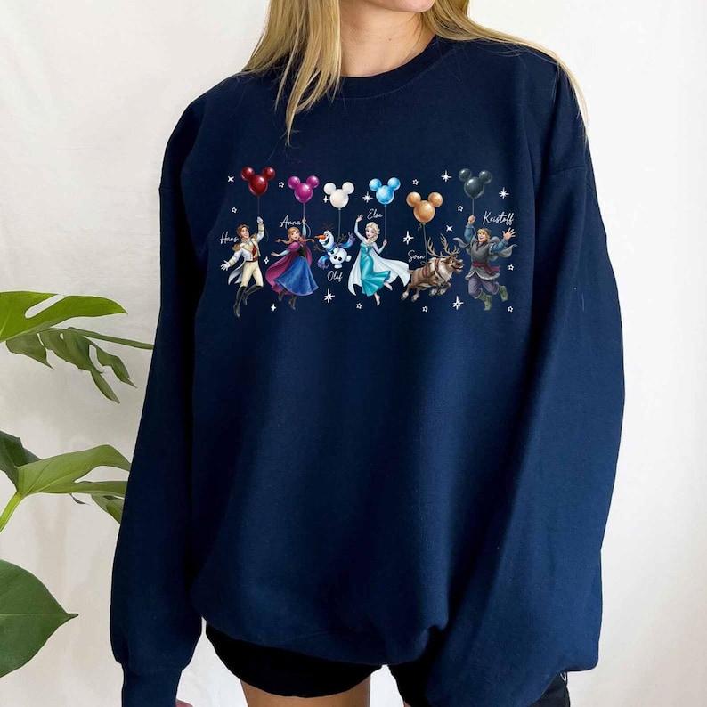 May include: Navy blue sweatshirt featuring a colorful graphic of characters from a popular animated movie. The characters are depicted with balloons in the shape of Mickey Mouse heads. Names are written above each character. A cozy and stylish garment.