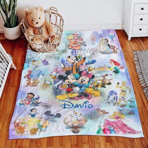 Op de afbeelding: Een kleurrijke Disney-deken met Mickey en Minnie Mouse, Donald Duck, Goofy en andere geliefde personages. De deken heeft de naam "David" en bevat afbeeldingen van Disney-prinsessen en andere personages.