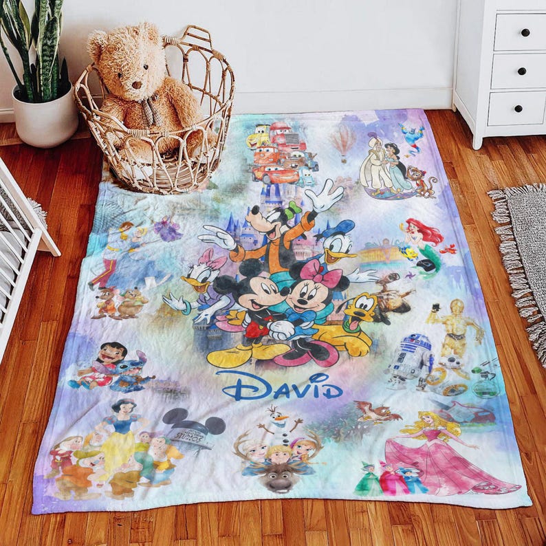 Op de afbeelding: Een kleurrijke Disney-deken met Mickey en Minnie Mouse, Donald Duck, Goofy en andere geliefde personages. De deken heeft de naam "David" en bevat afbeeldingen van Disney-prinsessen en andere personages.