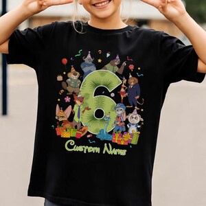 May include: A black short-sleeve t-shirt featuring a large green number six surrounded by various cartoon animal characters wearing party hats. The design includes colorful gift boxes, confetti, and the text Custom Name at the bottom.