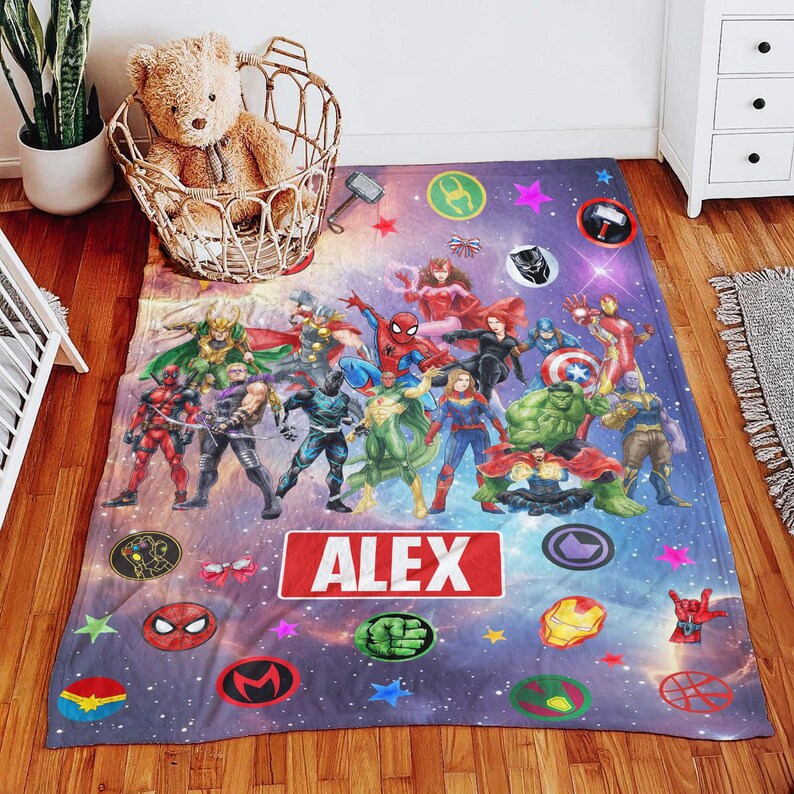 May include: A rectangular fleece blanket featuring a vibrant cosmic background filled with various Marvel superhero characters, including Spider-Man, Hulk, and Iron Man. The center displays a red rectangular name tag with the white text ALEX.