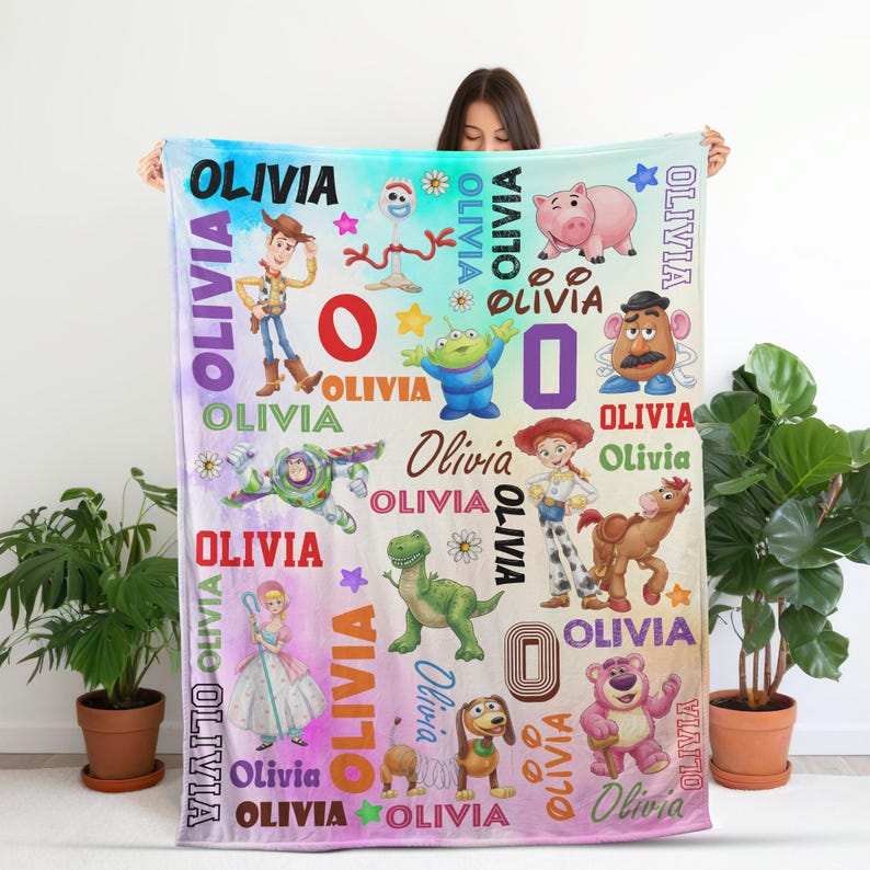 Op de afbeelding: Een zachte fleece deken met een kleurrijke gradi&euml;nt achtergrond en diverse Toy Story karakterillustraties waaronder Woody, Buzz Lightyear, Jessie en Rex. De naam Olivia is herhaaldelijk in verschillende lettertypes gedrukt.