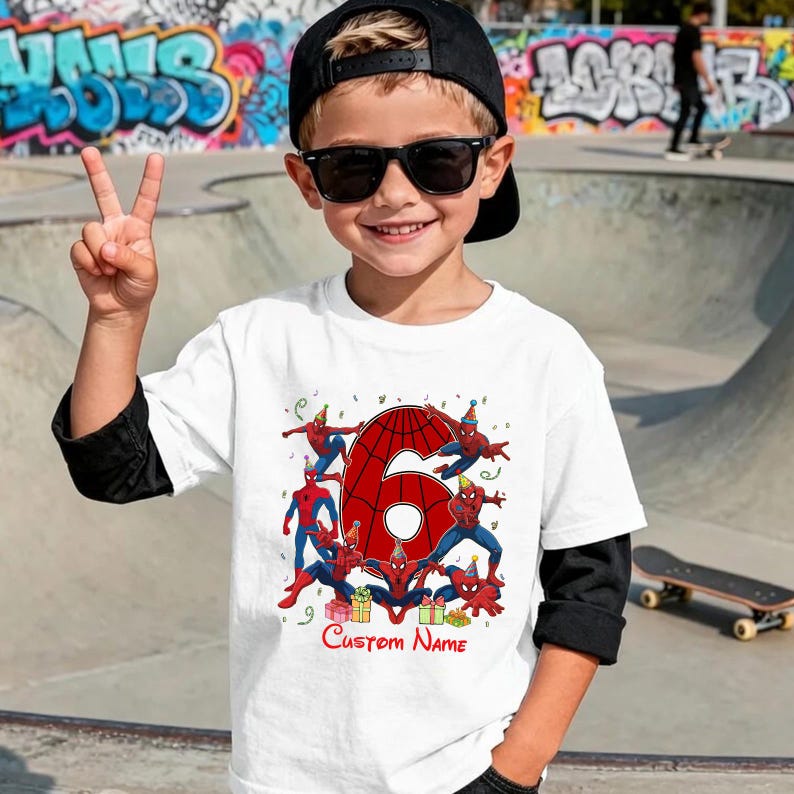 May include: A white short-sleeved t-shirt featuring a large red number six with a spiderweb pattern, surrounded by multiple Spider-Man figures wearing party hats, colourful gift boxes, and the red text Custom Name printed at the bottom.