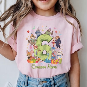 May include: A light pink t-shirt featuring a large green number six surrounded by various animated animal characters wearing party hats. The graphic includes colorful gift boxes, confetti, and the text Custom Name printed in green below the design.