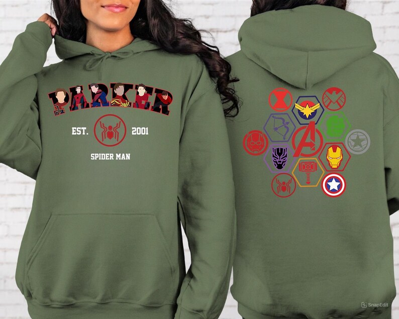 Puede incluir: Sudadera con capucha verde oliva con la palabra "PARKER" y la imagen de Spider-Man. La parte trasera muestra varios logotipos de superh&eacute;roes en un patr&oacute;n hexagonal. Tambi&eacute;n se ve el texto "EST. 2001 SPIDER MAN".