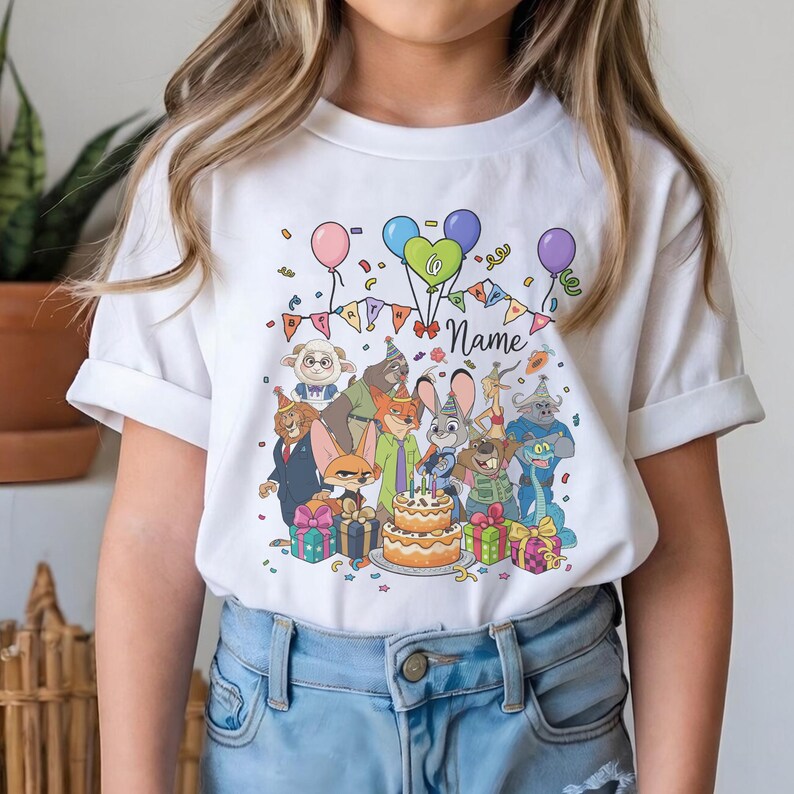 Puede incluir: Camiseta blanca con un dise&ntilde;o de cumplea&ntilde;os colorido con personajes de dibujos animados, globos, confeti y una tarta de dos pisos. El dise&ntilde;o incluye el n&uacute;mero 6 y espacio para un nombre. La camiseta la lleva una persona.
