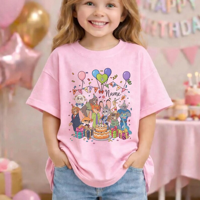 Puede incluir: Camiseta rosa de manga corta con una colorida escena de cumplea&ntilde;os de dibujos animados. El dise&ntilde;o incluye globos, confeti y una tarta. La camiseta tiene la palabra "Name" impresa, y personajes de dibujos animados.