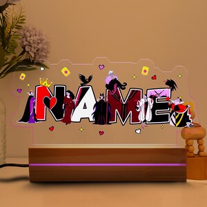 May include: A personalized night light featuring the name "NAME" in bold letters, each letter decorated with cartoon villain characters. The light sits on a wooden base with a purple glow, creating a whimsical and decorative accent.