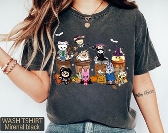 May include: Dark gray wash t-shirt with a Halloween-themed graphic. The design features cartoon characters dressed in costumes, arranged as if in coffee cups. Text at the bottom reads "WASH TSHIRT Mirenal black".