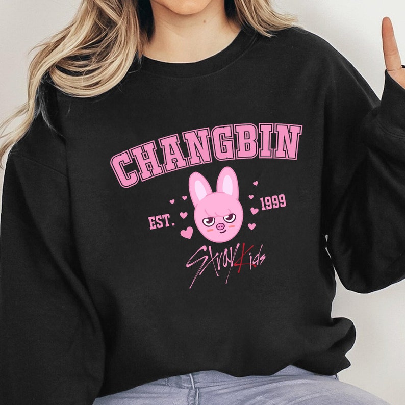 May include: Black sweatshirt featuring a pink graphic. The design includes the name "CHANGBIN", the year "1999", a bunny face, the text "Stray Kids", and hearts.