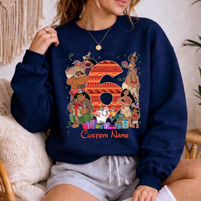 May include: A navy blue crewneck sweatshirt featuring a large orange patterned number six surrounded by various animated characters wearing party hats. The design includes colorful gift boxes and the red text Custom Name at the bottom.