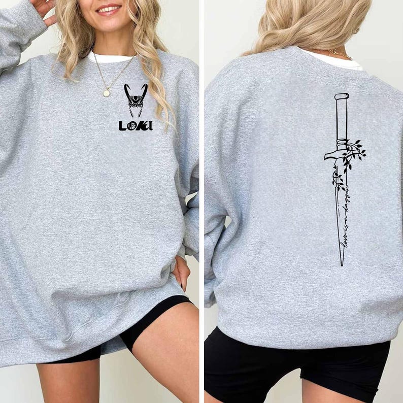 May include: A light gray sweatshirt with a white collar. The front features a black graphic of Loki's helmet and the name "LOKI". The back displays a black dagger design with the words "Worth a Strong".