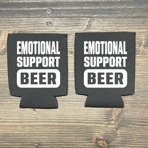May include: Two black foam beverage insulators with white text that reads "Emotional Support Beer".