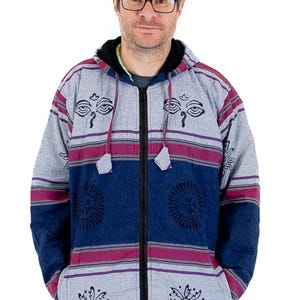 Può includere: Una giacca con cappuccio a righe grigie e blu con occhi ricamati neri e motivi floreali. La giacca ha una cerniera e due tasche.