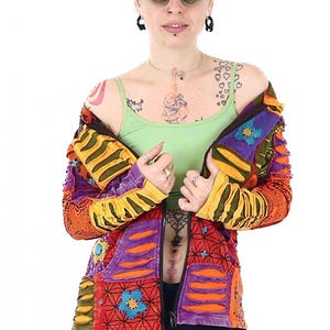 Pode incluir: Uma jaqueta colorida de patchwork com fecho de correr. A jaqueta é feita de diferentes tecidos e tem uma variedade de padrões, incluindo riscas, flores e padrões geométricos.