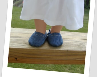 May include: A pair of blue denim baby shoes on a wooden surface.