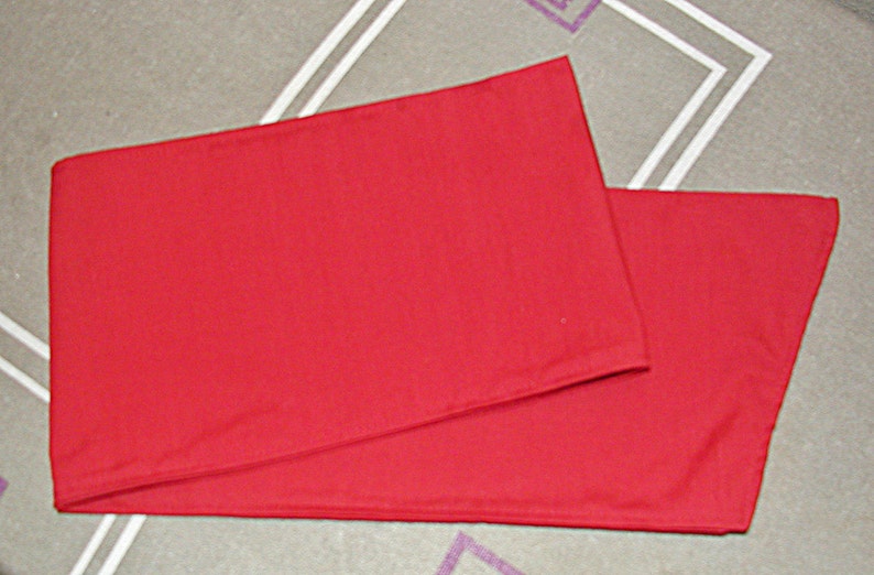 May include: A red fabric table runner, folded in half, with a smooth, even texture.