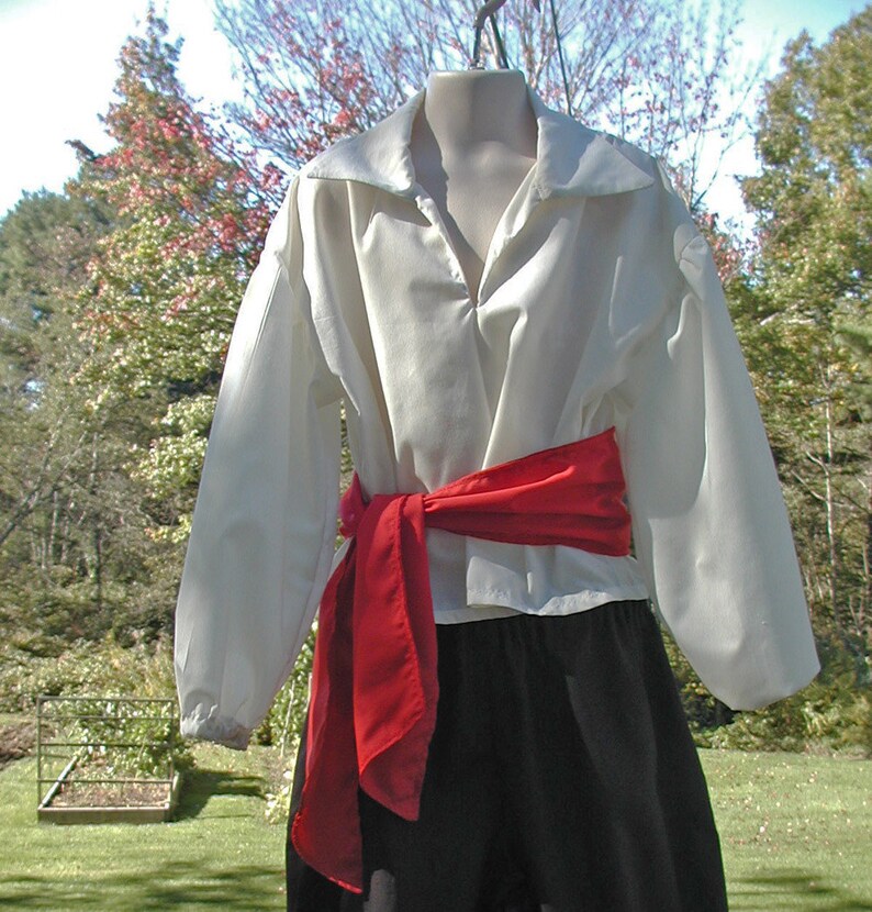 May include: A white shirt with a red sash tied around the waist. The shirt has a collar and long sleeves. The sash is tied in a bow at the front.