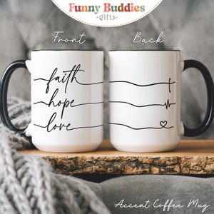 May include: White accent coffee mug with black handle and rim. The front of the mug features the words "faith, hope, love" in a flowing script. The back of the mug has a line design with a cross, heartbeat, and heart symbol.