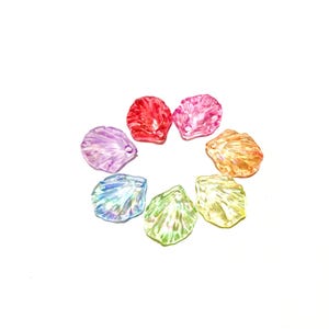 May include: A collection of eight colorful, shell-shaped beads arranged in a circle. The beads are translucent, with hues of red, pink, orange, yellow, green, blue, and purple. Each bead has a small hole for stringing.