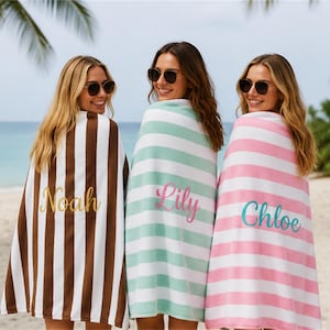 May include: Three beach towels featuring embroidered names. The first towel has vertical brown and white stripes with the name Noah in gold. The second has horizontal mint green and white stripes with the name Lily in pink. The third has horizontal pink and white stripes with the name Chloe in teal.