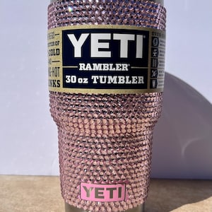 May include: A pink Yeti Rambler 30 oz tumbler with a pink rhinestone design. The tumbler has a stainless steel lid and base.