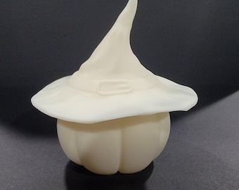 Può includere: Una zucca di ceramica bianca con un cappello da strega in cima. Il cappello ha una punta appuntita e un ampio bordo.