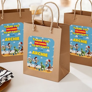 May include: Three brown paper gift bags with rope handles. Each bag features a blue sticker with the text "THANK YOU FOR COMING TO MY PARTY From ARCHIE" and a cartoon image of characters.