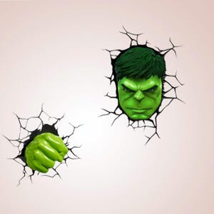 May include: A wall decoration depicting the Hulk's head and fist emerging from a cracked wall. The Hulk is green with an angry expression, and his fist is clenched. The cracks are black, creating a 3D effect, suitable for a child's bedroom.