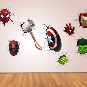 May include: Wall decals depicting superhero emblems and characters such as Spider-Man, Thor's hammer, Captain America's shield, Iron Man's mask, Hulk's fist and face, and Deadpool's mask. The decals create a 3D effect of breaking through a wall.