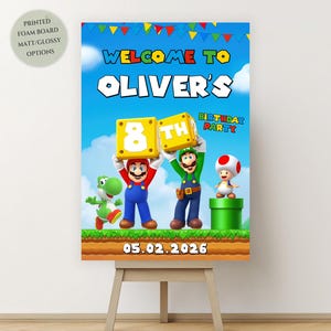 Peut inclure: Une affiche colorée pour une fête d'anniversaire avec des personnages de Mario. L'affiche indique "Bienvenue à la fête d'anniversaire d'Oliver" avec la date du 05.02.2026. L'affiche est présentée sur un chevalet en bois.