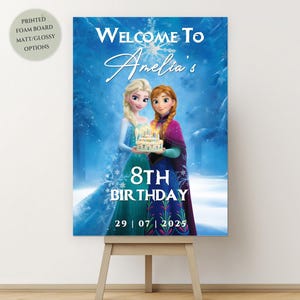 Puede incluir: Un letrero de cumpleaños con los personajes Elsa y Anna de la película Frozen. El letrero dice "Bienvenida al 8º Cumpleaños de Amelia" con la fecha 29|07|2025. El letrero está sobre un caballete de madera.