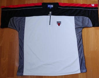 May include: White, black, and gray athletic shirt with a red and black Chicago Bulls logo. The shirt has a zipper and a Starter brand logo.