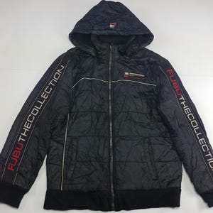 May include: Black quilted hooded jacket with the text "FUBU THE COLLECTION" in red and white on the sleeves. The jacket has a full-length zip and a small logo patch on the chest. The jacket is a dark colour.