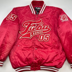 Può includere: Giacca bomber in satin rosso con bordini bianchi e rossi. La giacca presenta il testo "Fubu League 05" in lettere bianche sul davanti. La giacca ha anche una cerniera bianca e un colletto bianco.
