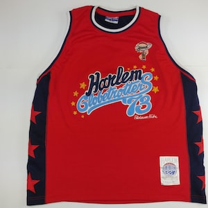 May include: Red Harlem Globetrotters basketball vest with navy blue accents and star details. Features the team name and "73" in a stylized font, along with a cartoon character graphic. Includes a tag with the team logo.
