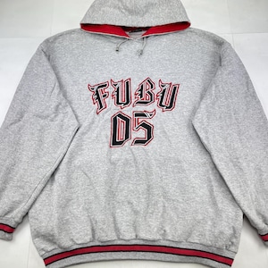 May include: A grey hooded sweatshirt with red detailing. The front displays the text "FUBU 05" in a black and red design. The hood lining and cuffs are red with black stripes.