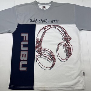 May include: A grey, white, and navy blue short-sleeved t-shirt with a large headphone graphic. The shirt features the word "FUBU" vertically on the left side and the text "Belle Street Art" on the top.