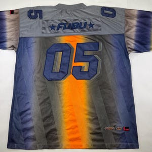 May include: A grey, blue, and orange Fubu jersey with the number 05 on the front and back. The jersey has a gradient design and the Fubu logo on the chest.