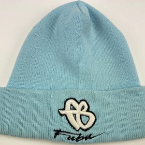 May include: A light blue beanie with a white and black embroidered logo that says "Fuelbox" on the front.