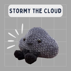 Peut inclure: Un jouet en peluche en forme de nuage gris crocheté avec des jambes en crochet noir. Le jouet a un visage souriant avec des yeux noirs et une bouche cousue. Le jouet est étiqueté "Stormy the Cloud".