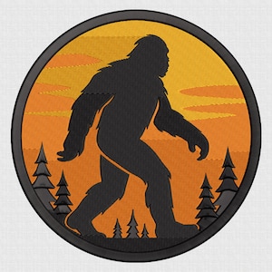 May include: A black embroidered patch featuring a silhouette of Bigfoot walking across an orange and yellow sunset scene. The patch is circular with a black border and includes the text "5 SIZE" at the top and embroidery file formats at the bottom.