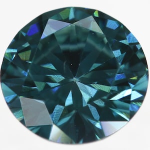May include: A round, faceted, teal blue gemstone with a brilliant cut. The gemstone is set in a clear, colorless setting.