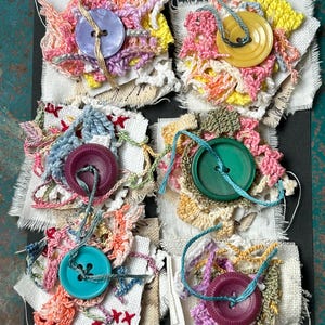 May include: A set of three ceramic mugs with a speckled, matte finish. The mugs are in shades of cream, light gray, and dark gray. Each mug has a simple, minimalist design and a rounded handle.