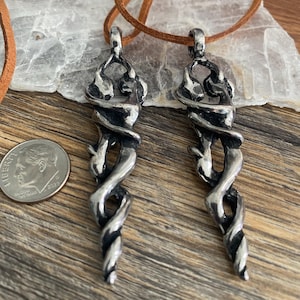 May include: Two silver pendant necklaces with a twisted, snake-like design. The pendants are hanging from brown leather cords.