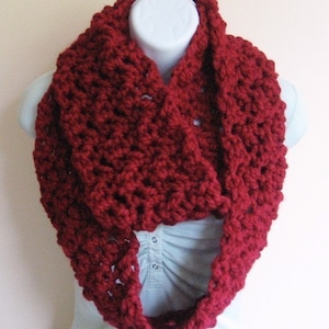May include: A deep red crocheted infinity scarf. The scarf is made with a chunky yarn and has a simple, textured stitch pattern.