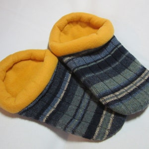 May include: A pair of cozy, handmade slipper socks. The socks feature a blue and gray striped pattern with a gold-colored fleece lining and cuff. These warm socks are perfect for lounging at home.