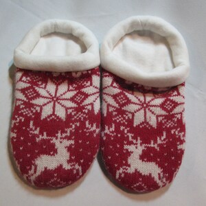 May include: Pair of red and white knitted slippers with a snowflake and reindeer pattern.